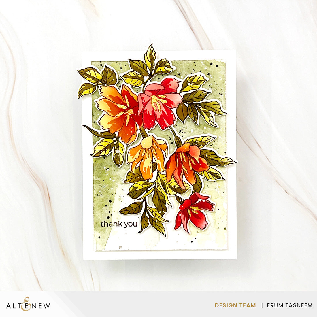 A handmade greeting card featuring layered floral designs in red, orange, and yellow with green leaves on a textured light green background, displayed on a white marble surface.