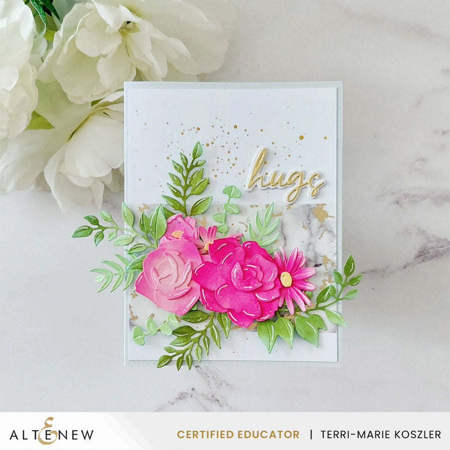 A handmade greeting card with layered pink paper flowers, green leafy stems, gold glitter, and the word 'hugs' in gold script, displayed on a light marble surface with white flowers in the background. Alteneew branding and a certified educator badge are visible at the bottom. Altenew EZ Arrangement: Garden Mix Layering Die Set card ideas