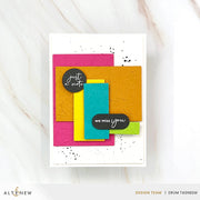 A handmade layered greeting card with textured paper in pink, mustard, yellow, teal, and lime green, featuring black oval labels with white script text reading 'just a note' and 'we miss you', displayed on a white marble surface. Altenew Nesting A2 Panels Die Set card ideas