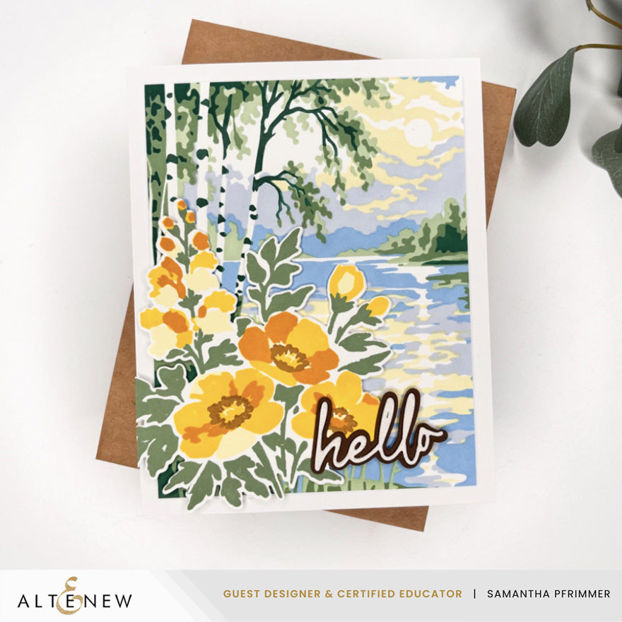 A handmade greeting card featuring a colorful landscape painting of a lake with yellow flowers in the foreground and the word 'hello' in script, displayed on top of a brown envelope against a white background. Altenew Craft Your Life Project Kit: Painterly Perfection card ideas