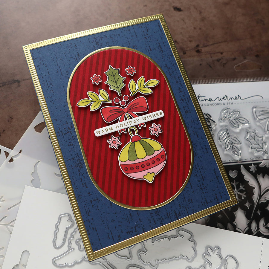 A handmade Christmas greeting card with a navy blue background, a red striped oval center, and a gold border. The card features a pink bow, green holly leaves, a colorful ornament, and the text 'WARM HOLIDAY WISHES'.