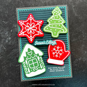 A handmade Christmas-themed card featuring four layered paper cutouts: a red snowflake, a green Christmas tree, a green house with white trim, and a red mitten with a white snowflake. The card has a dark teal striped background with a turquoise scalloped border and reads 'Season's Eatings' and 'MAY YOUR HOLIDAY BE FILLED WITH SWEET MOMENTS.