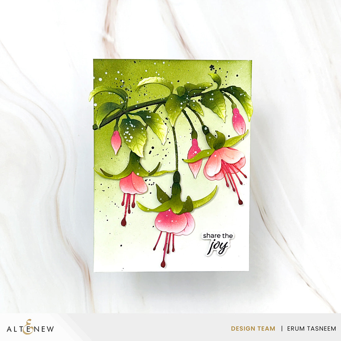 A handmade greeting card featuring a watercolor illustration of pink fuchsia flowers and green leaves on a white background with a green watercolor wash. The card has the text 'share the joy' printed on it.