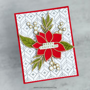 A handmade Christmas greeting card featuring a red poinsettia with green leaves and a 'Merry Christmas' banner, set against a white patterned background with a red border, photographed on a light gray marble surface.