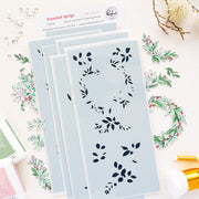 A set of layered stencils from the brand Pinkfresh Studio, shown in a styled flat-lay with coordinating floral stamps, ink pads, and craft tools on a white background.