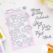 Simply Said Dies by Pinkfresh Studio die-cut card stock sheet with 8 letter-shaped dies, styled on a white background with black script text reading 'Happy Birthday Celebrate Miss you Just a note Thank you. Hello'.