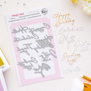 Simply Said Press Plates by Pinkfresh Studio on a white card, styled on a light beige surface with gold and silver metallic lettering examples and craft tools.