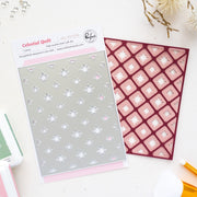 Celestial Quilt metal craft die set by Pinkfresh Studio, featuring a silver-gray sheet with snowflake cutouts and a dark red patterned sheet, displayed on a white surface with crafting props.