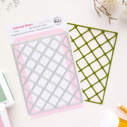 A packaged metal die set labeled 'Celestial Weave' by Pinkfresh Studio, shown on a light surface with the die cutout and backing card visible. The product is photographed in a styled flat-lay with a few small craft props around it.