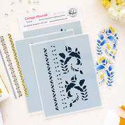 Three Cottage Flourish layering stencils by Pinkfresh Studio with floral and scroll cutouts, displayed on a light beige surface with decorative blue and gold stamped sheets and a brand card.