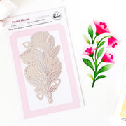 A packaged floral die-cut metal stamp set by Sweet Bloom, shown on a white background with a matching pink and green floral illustration beside it. The package reads Sweet Bloom and shows a single leafy flower die design. Pinkfresh Studio - Sweet Bloom Die