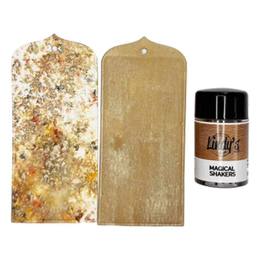 Two gold-colored tags with a hole at the top, shown next to a small jar of Lindy's 'Magical Shakers Cedar & Sass' powder on a plain white background.
