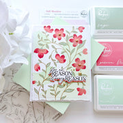 A handmade floral card with the phrase 'for REASON & every REASON' in layered text, styled with matching green envelopes and Pinkfresh Studio premium dye ink pads in sage, passion fruit, and mint on a white background.