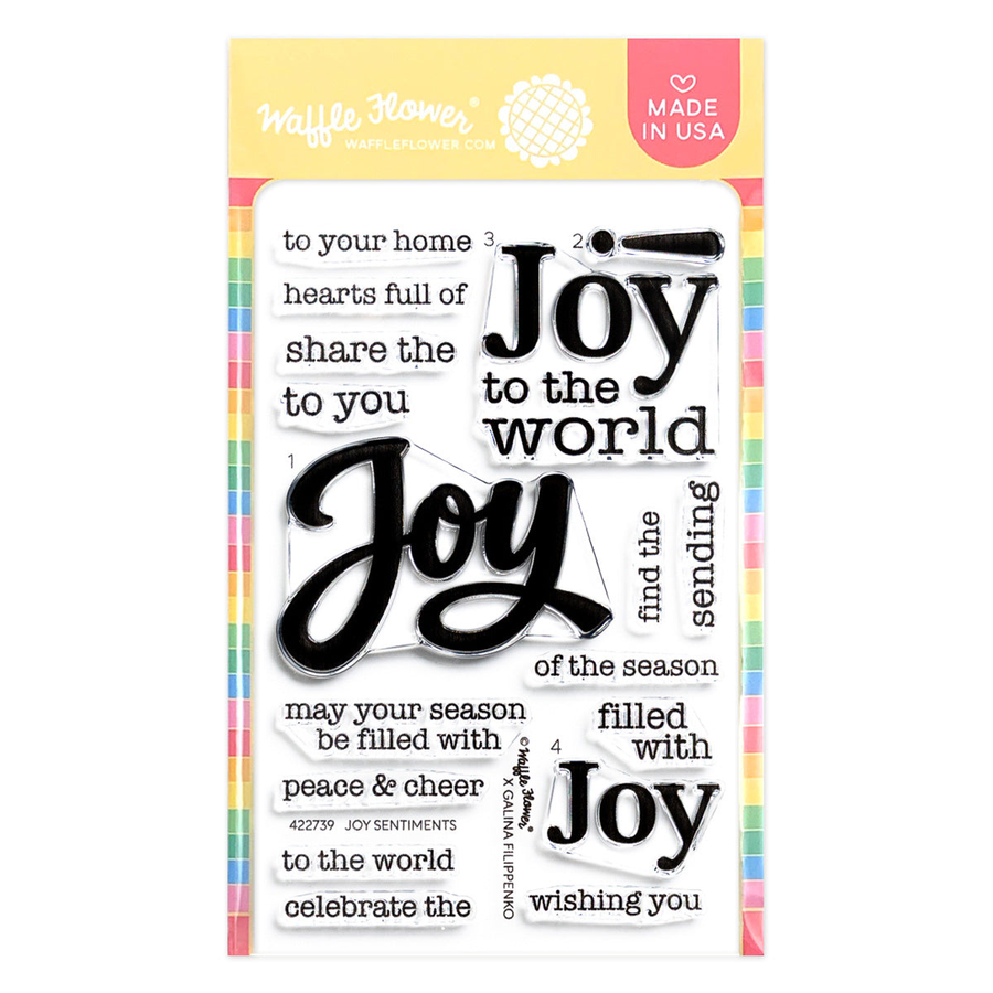 Waffle Flower Joy Sentiments Stamp Set in its original packaging, featuring various black and white holiday-themed phrases like 'Joy to the world' and 'find the sending joy' on a white background with a pastel striped border.