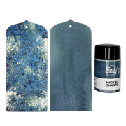 A set of two blue textured tags shown on a white background, alongside a small bottle of Lindy's 'Magical Shakers Deep River Denim' ink. The set includes one tag with a blue and white glittery abstract pattern and one medium blue tag with a subtle sheen.
