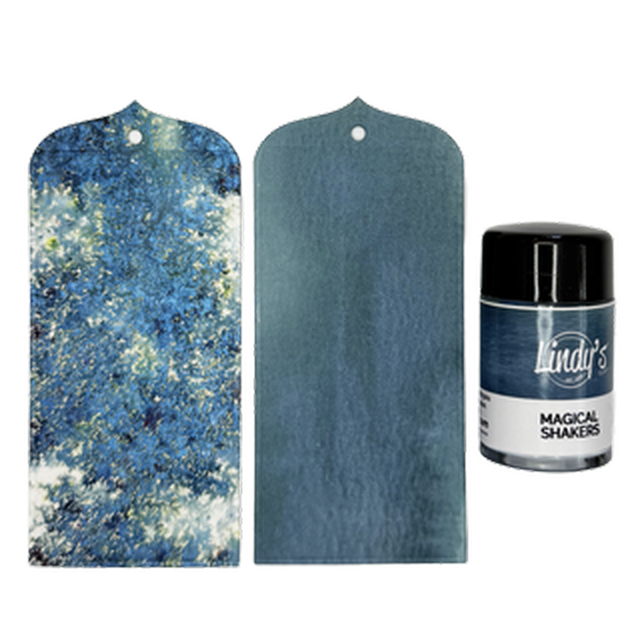 A set of two blue textured tags shown on a white background, alongside a small bottle of Lindy's 'Magical Shakers Deep River Denim' ink. The set includes one tag with a blue and white glittery abstract pattern and one medium blue tag with a subtle sheen.