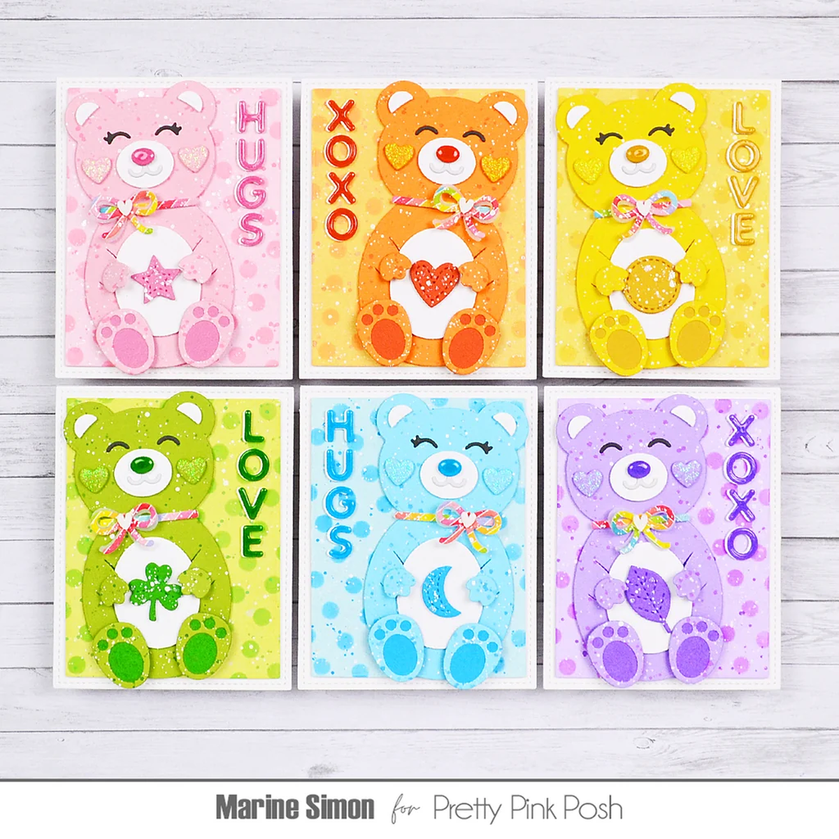 Six handmade colorful teddy bear greeting cards arranged in a 2x3 grid on a white wood background. The cards feature different bear designs in pink, orange, yellow, green, blue, and purple, with text reading HUGS, LOVE, XOXO, and names Marine Simon and Pretty Pink Posh.