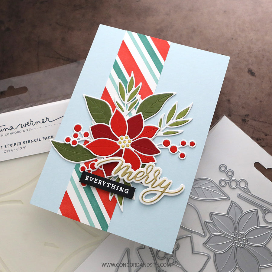 A handmade holiday greeting card with a layered poinsettia design, green leaves, red berries, and a black banner reading 'Merry Everything' on a light blue cardstock. The card is styled on top of a Stencil Werner holiday stencil pack box and a metal die-cut stencil sheet.