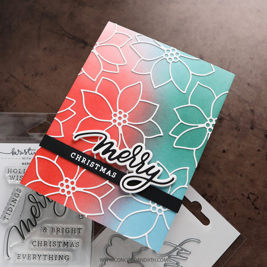 A handmade Christmas greeting card with a red-to-blue gradient background, white floral line art, and a black banner reading 'Merry Christmas.' Clear stamp packages are partially visible underneath on a brown textured surface.