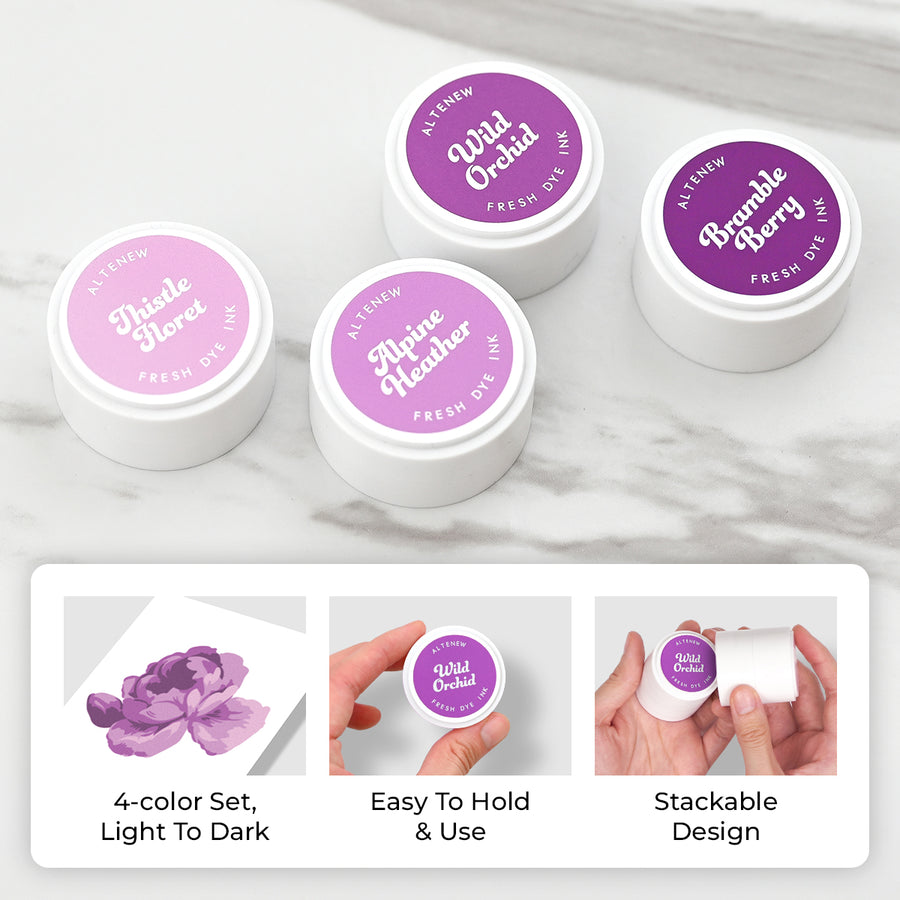 Four small round jars of ink with white lids and purple labels are arranged on a light marble surface. The labels read Althea New and scent names including Disheled Clover, Alpine Heather, Wild Orchid, and Bramble Berry. Altenew Highland Flora Fresh Dye Ink Mini Pods