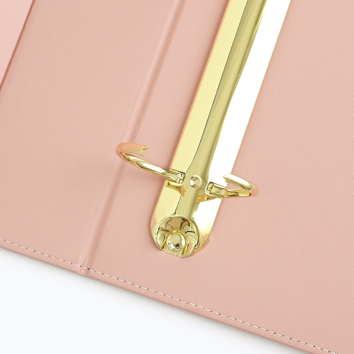 Close-up of a rouge ring binder cover with a shiny gold metal ring and white interior pages. 
