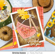 A handmade autumn-themed greeting card featuring an acorn with glittery pink filling, yellow leaves, and the words 'Grateful for you!' and 'Autumn Joy', displayed on a styled flat-lay background with other craft supplies.
