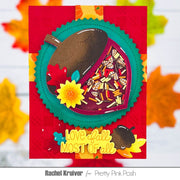 A handmade autumn-themed layered card featuring a die-cut leaf design with a brown acorn, colorful confetti-filled window, yellow flower, and the phrase 'Love fall most of all' on a red background with blurred fall leaves.