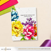 A handmade greeting card with colorful watercolor-style flowers and the printed quote 'today felt like making a card a little joy for me,' photographed on a light beige surface with paper and ribbon props. ALTENEW branding and 'Ambassador & Certified Educator | Aditi Mahajan' appear at the bottom.