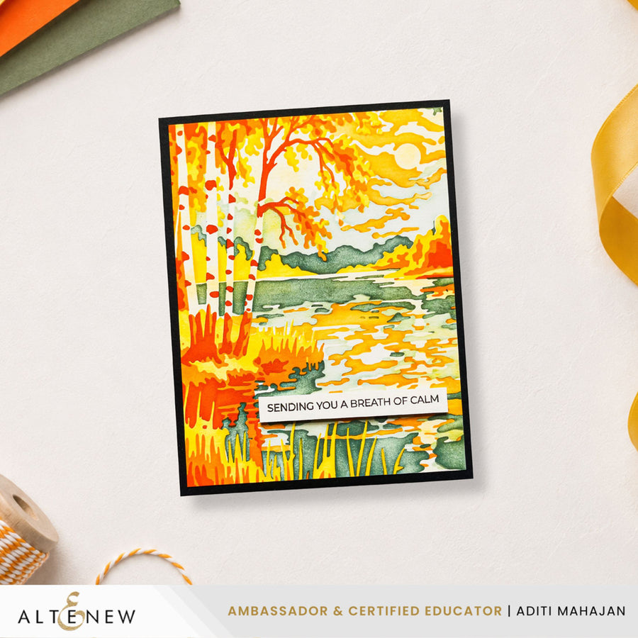 A handmade greeting card featuring a colorful autumn landscape with trees, grass, and a lake, displayed on a light surface with decorative ribbon and paper props. The print includes the text 'SENDING YOU A BREATHE OF CALM' and the brand name 'ALTENEW' appears at the bottom. Altenew Craft Your Life Project Kit: Painterly Perfection card ideas