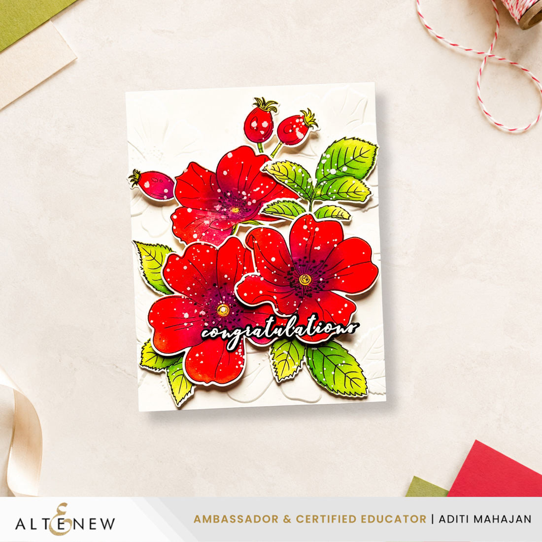 A handmade congratulations card featuring three red flowers with green leaves and red berries, with the word 'congratulations' in script. The card is displayed on a light beige surface with craft props, and an ALTÉNEW banner is visible at the bottom. Altenew One-Go: Briar Blossoms card ideas