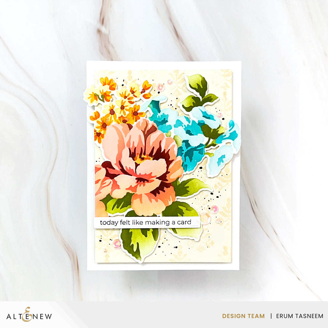 A handmade layered card featuring a large peach flower, blue flowers, yellow blossoms, and green leaves on a cream background with a small banner reading 'today felt like making a card'. The card is photographed on a light marble surface, with Altenew and Erum Tasneem branding visible at the bottom.