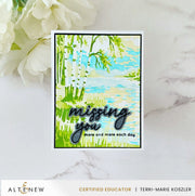 A handmade greeting card with a watercolor-style landscape of green trees and blue sky, featuring the text 'missing you more and more each day' in black script. The card is displayed on a white marble surface next to white flowers, with an Altenew Certified Educator banner at the bottom. Altenew Craft Your Life Project Kit: Painterly Perfection card ideas