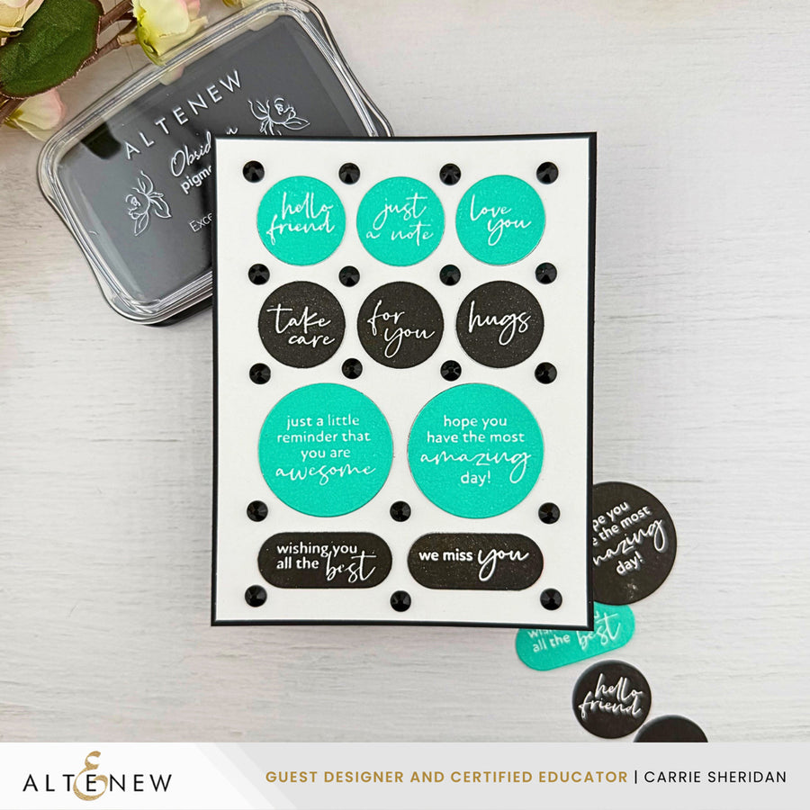 A handmade greeting card with black polka dots and teal and black circles containing handwritten-style phrases, displayed on a light wood surface with an Altenew ink pad and a few loose stickers nearby. Altenew One-Go: Solid Circular Sentiments Press Plate card ideas