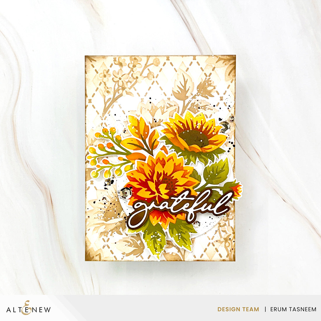 A handmade greeting card featuring a floral design with sunflowers, green leaves, and the word 'grateful' in cursive, displayed on a white marble surface. The card is branded with 'ALTENew' and 'Design Team | Erum Tasneem' at the bottom.