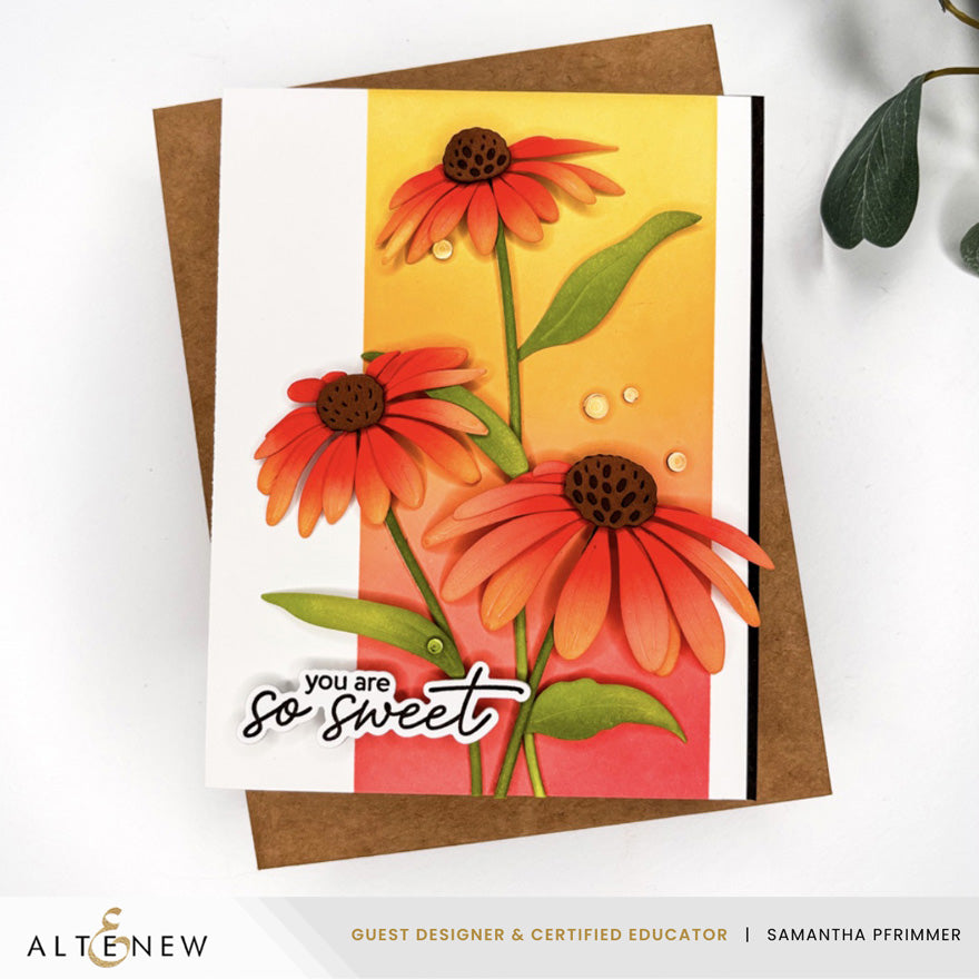 A handmade greeting card featuring three orange-red coneflowers with green leaves on a yellow and pink striped background, with the text 'you are so sweet' in black script. The card is displayed on top of a brown kraft envelope against a white background with a decorative leaf in the corner. Altenew Craft-A-Flower: Coneflower Layering Die Set card ideas