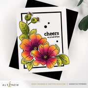 A handmade greeting card with a white background, featuring two large orange and pink flowers with green leaves and the text 'cheers so proud of you'. The card is styled on top of a black envelope, with a white surface and green leaves in the background. Altenew One-Go: Briar Blossoms card ideas