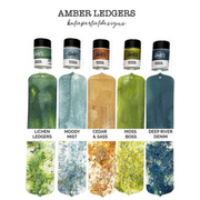 Five small jars of ink or pigment labeled 'Lindy's Gang' are shown above six matching rectangular color swatches, with text reading 'AMBER LEDGERS' and shade names including Lichen Ledgers, Moody Mist, Cedar & Sass, Moss Boss, and Deep River Denim on a white background. Lindy's Gang Amber Ledgers by Katie Pertiet Magical Shimmer Shaker Set (5 Pack)