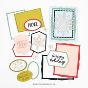 A flat lay of multiple handmade holiday greeting cards and decorative paper elements on a white background, including scalloped frames, snowflake cutouts, and phrases like “NOEL,” “HOLLY JOLLY,” and “Happy Holidays.”.