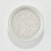 Clear seed beads filled with white glitter, displayed in a small white ceramic bowl on a clean white background. Spellbinders Clear Iridescent Beads