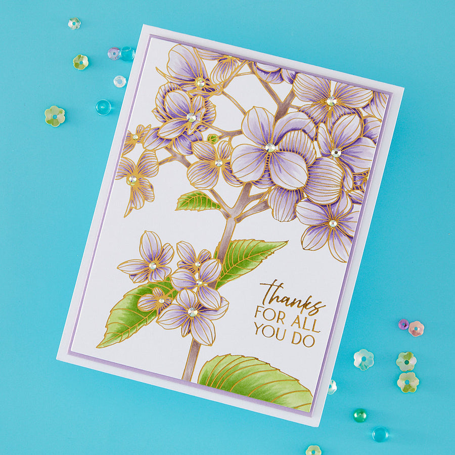 A handmade greeting card with a white background, featuring a detailed illustration of light purple hydrangea flowers with green leaves and gold outlines. The right side of the card has the printed text 'thanks FOR ALL YOU DO' in gold.