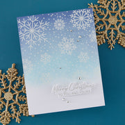 A handmade Christmas greeting card with a blue-to-white gradient background, embossed white snowflakes, and silver rhinestone embellishments. The card features the embossed text 'Merry Christmas TO YOU AND YOURS' at the bottom.
