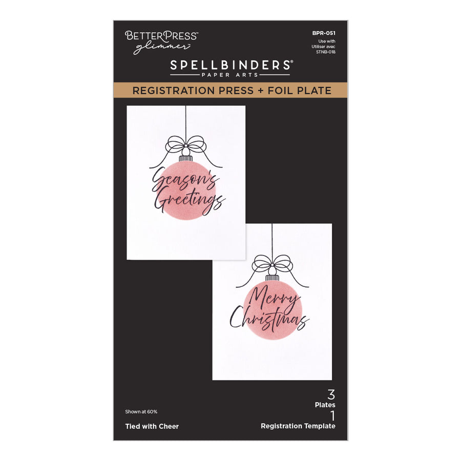 BetterPress Glimmer Spellbinders Paper Arts Registration Press and Foil Plate package, featuring two sample holiday cards with pink ornament graphics and black text on a black card backing. Spellbinders Tied with Cheer Registration Press + Foil Plate