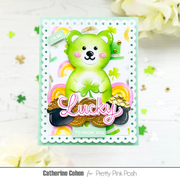 A handmade St. Patrick's Day greeting card featuring a cute green bear with a shamrock, layered with rainbow and pot-of-money details, and the word 'Lucky' in pink script.