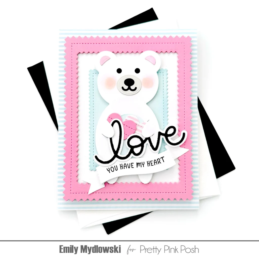 A handmade layered greeting card featuring a white polar bear holding a pink heart, surrounded by pink and light blue scalloped borders, with the words 'love YOU HAVE MY HEART' in black script and block lettering. The card is displayed on a white background with black and white paper accents, and the text 'Emily Mydlowski for Pretty Pink Posh' appears at the bottom.
