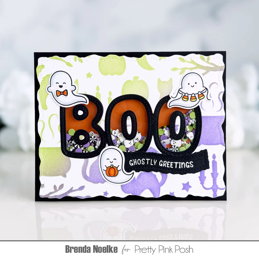 A handmade Halloween greeting card featuring the word 'BOO' in large orange and black letters filled with ghost-themed shaker confetti. The card has scalloped edges, a black border, and cute cartoon ghosts.
