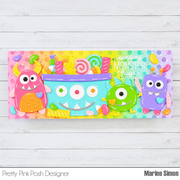 A colorful handmade wall hanging or plaque featuring three cartoon monster faces and candy motifs, with the text 'sending MONSTER hugs' on a white wood background. The product is shown with branding text at the bottom: Pretty Pink Posh Designer and Marine Simon.