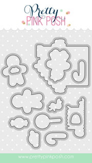 A sheet of craft dies from Pretty Pink Posh, featuring various cloud, leaf, and abstract shapes in silver metal over a white polka dot background, with the brand name at the top and a website URL at the bottom. Pretty Pink Posh Christmas Gingerbread Coordinating Dies