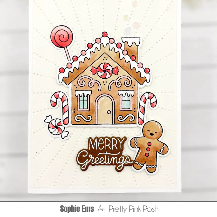 A festive greeting card featuring a gingerbread house, candy canes, a lollipop, a gingerbread person, and the words 'Merry Greetings' on a white background. The card is branded with 'Sophie Ems for Pretty Pink Posh' at the bottom.