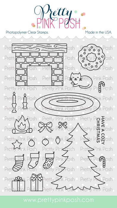 A sheet of photopolymer clear stamps from Pretty Pink Posh, featuring Christmas-themed illustrations including a fireplace, cat, candy cane, stockings, tree, gifts, and bows on a white background with a green footer. Pretty Pink Posh Cozy Christmas Stamp Set