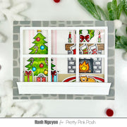 A handmade Christmas-themed window card with six panes showing holiday scenes: a Christmas tree, candles, stockings, a fireplace, candy canes, and a cat. The card is styled on a white surface with festive greenery and red ornaments around it.
